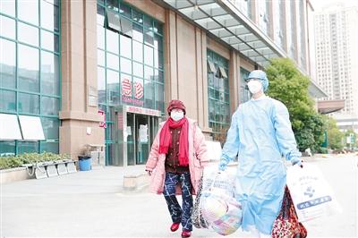 武汉市中心医院的医护人员送患者出院。李蓓摄/光明图片