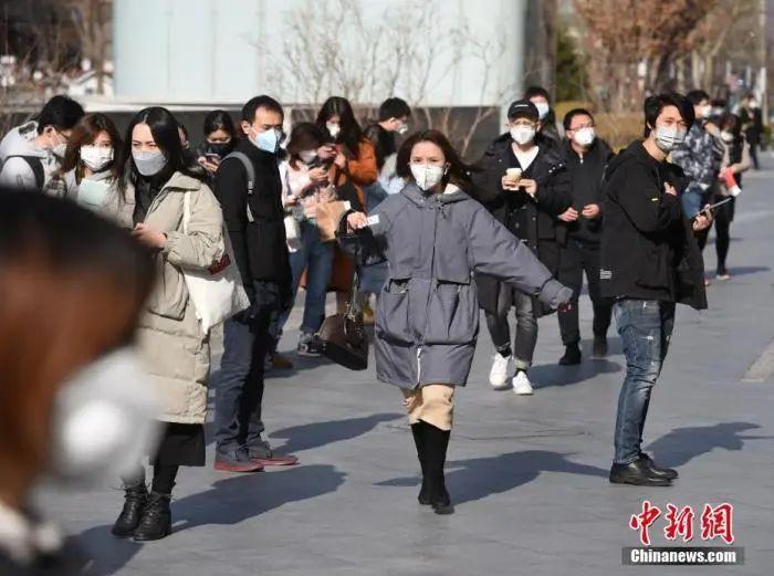3月2日,北京一些企业的员工在写字楼入口处排队,按要求提供身份信息及接受体温检测后入内办公。中新社记者 侯宇 摄