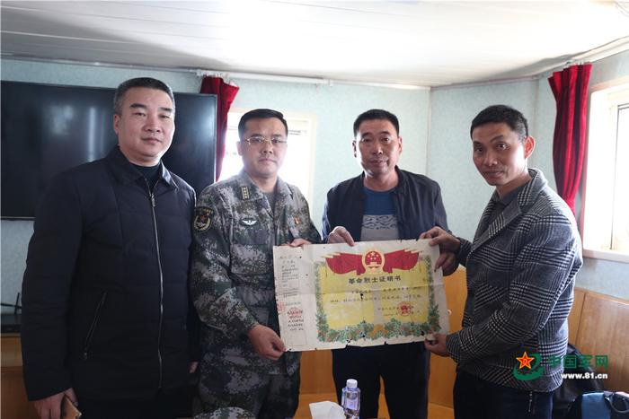 烈士亲属向军地领导展示革命烈士证明书。