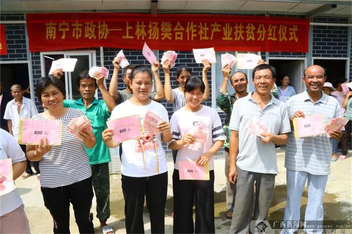 贫困户、村民们拿到了分红都露出了灿烂的笑容。广西日报记者 何学俏 摄