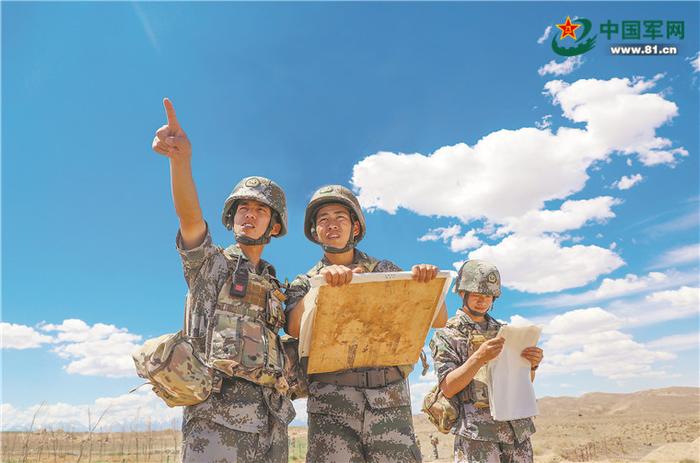 新疆军区某团榴炮营二连连长张任常(中)和指导员刘晓云(左),在训练中结合地形图现地指示目标。黄飞皓摄