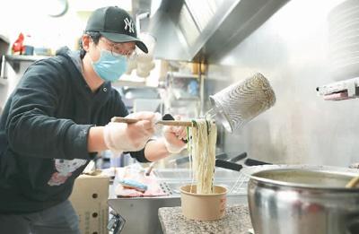 图为2020年4月,在澳大利亚堪培拉一家参加“跨店点单、一单运费”活动的华人餐馆,工作人员捞起煮好的面条。 储 晨摄(新华社发)