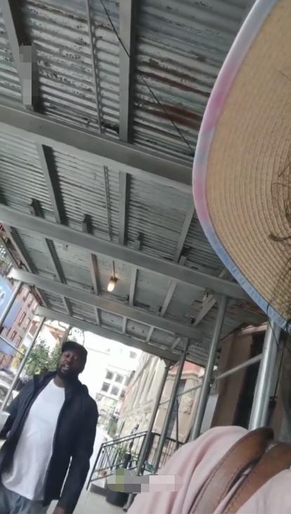 非裔男子走近华裔女子,并进行辱骂