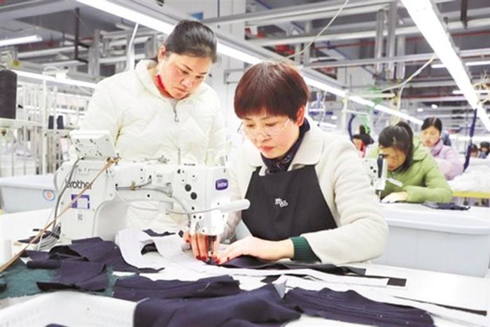 2月8日，在位于毕节高新区的贵州星美服饰有限公司生产车间，老员工带领新员工进行服装生产。