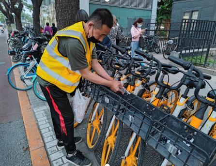 ▲朝阳区亮马桥地铁口共享单车运维员清理小广告 摄影:朱建国