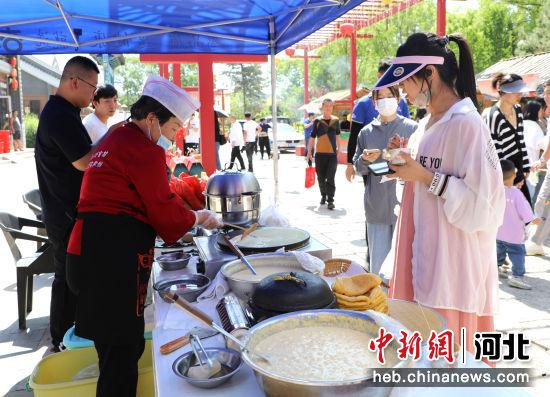游客在摊位前参观体验美食。 秦晶晶 摄