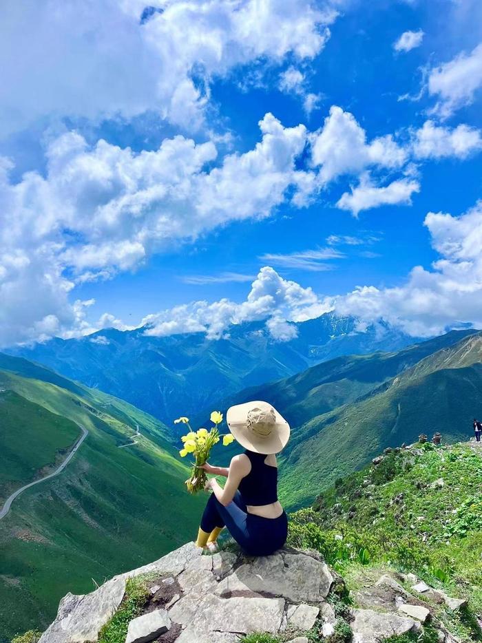 ↑女游客在巴朗山手持绿绒蒿拍照