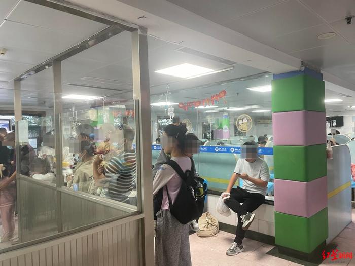 ▲10月23日,该医院输液室,家长抱着小孩排队