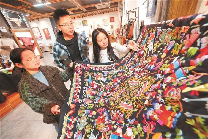 图为11月13日，工作人员在施秉一家苗绣企业展厅给客人介绍苗绣产品。
