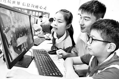 大学生志愿者指导外来务工人员子女上网学习。石玉成摄/光明图片