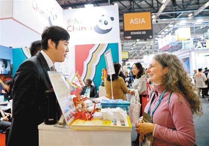 11月6日，一名女子在英国伦敦世界旅游交易会中国展区与工作人员交流 图：新华社