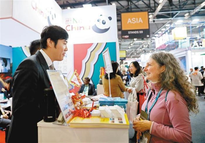 11月6日,一名女子在英国伦敦世界旅游交易会中国展区与工作人员交流 图:新华社
