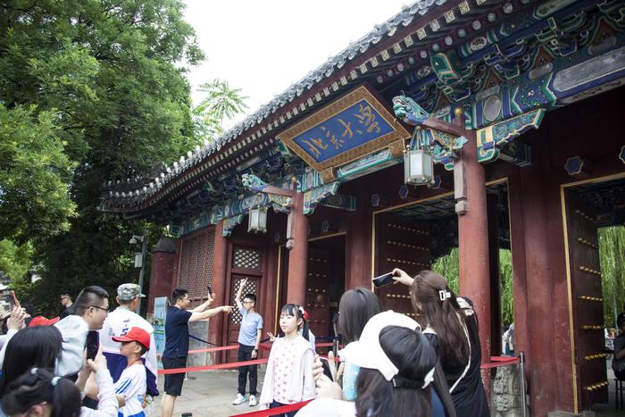 ▲暑假期间,不少家长陪伴孩子来到北京大学西门打卡留影。据ICphoto