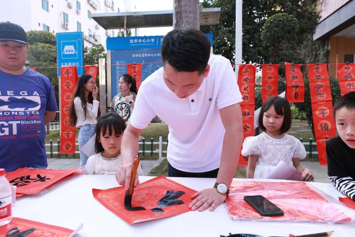 龙华中心小学举行义写春联活动，师生挥笔泼墨传递祝福与温暖