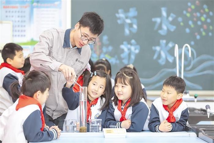 3月21日，在山东省青岛弘德小学，污水处理厂讲解员指导学生做实验。