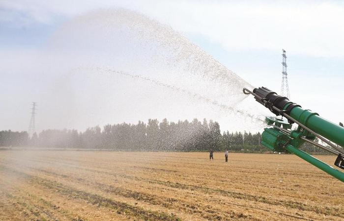 农民使用卷盘式喷灌机为玉米幼苗浇水
