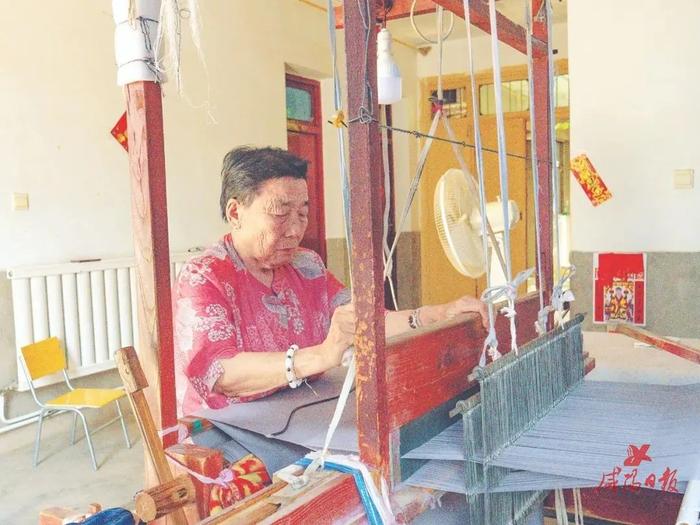 李凤英在织布机前有条不紊地织布。