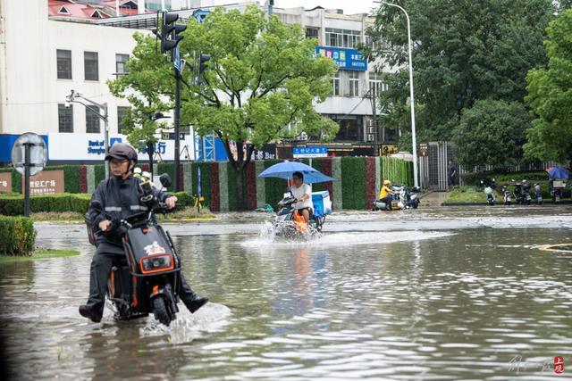 浦东遭遇暴雨，市政工人全力排水，外卖小哥“摆渡”市民过街