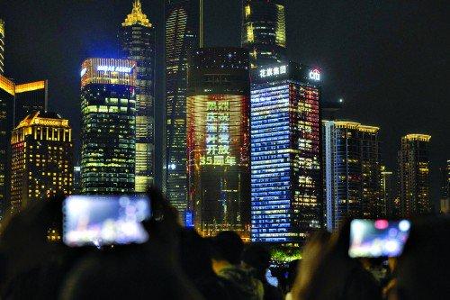 人们在外滩拍摄对岸陆家嘴庆祝浦东开发开放35周年光影秀。新华社 图