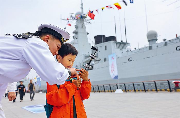 4月22日,海军在上海举行的舰艇开放活动中,一个小朋友在海军战士指导下体验使用三杯风向风速仪。新华社记者 方喆 摄