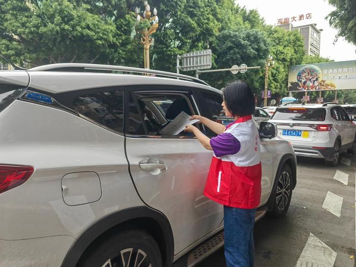 5月2日,云南省墨江哈尼族自治县一名志愿者向游客发放节庆活动行程单。(墨江县融媒体中心供图)