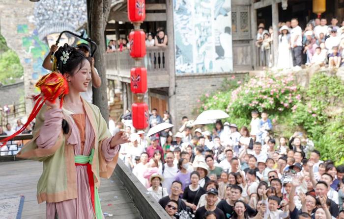 5月1日,在贵州省遵义市乌江寨景区,身着传统服饰的年轻人与游客进行抛绣球互动。新华社发(袁福洪摄)
