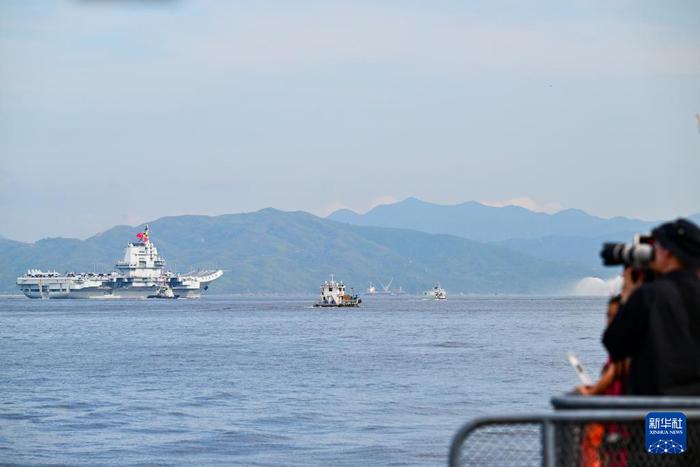 7月3日,人们在岸上拍摄海军山东舰抵达香港。新华社记者 朱炜 摄