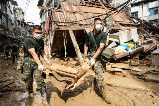 官兵奋力帮助受灾点清淤重建 归王彬摄