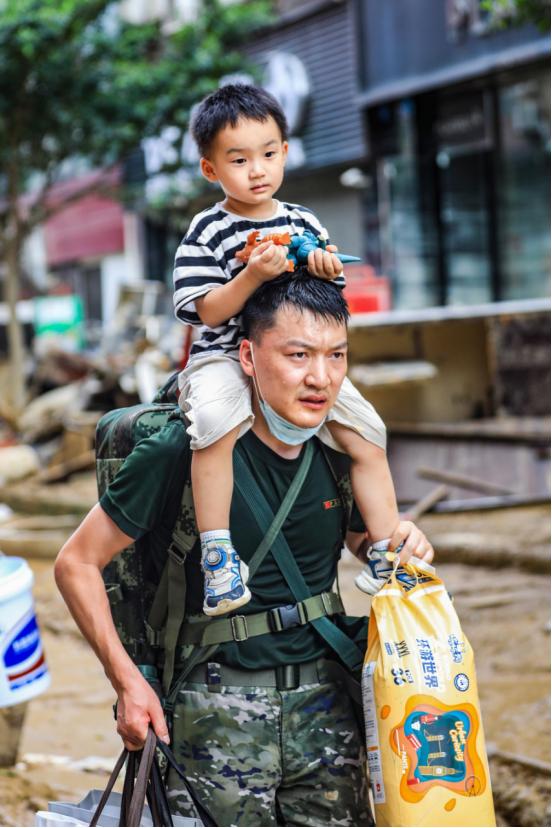 党员突击队队员梁腊强在救灾一线帮助被困群众撤离 归王彬摄