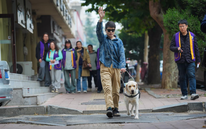 (图:视障人士正在训导师的指导下学习如何使用导盲犬。完成共同训练后,导盲犬将成为他们最忠诚的朋友。)