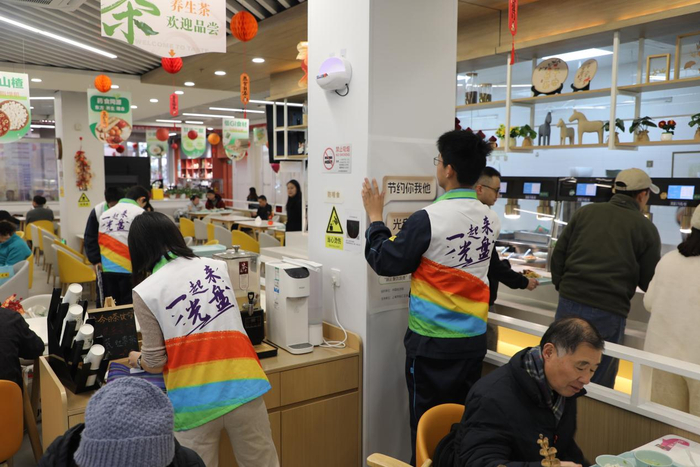 志愿者们将“制止餐饮浪费”宣传海报张贴在餐厅醒目位置。 中国经济网 王岩/摄
