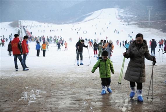 八达岭滑雪场，一对母子正走向游客中心，由于地面湿滑，母亲提醒孩子要小心。