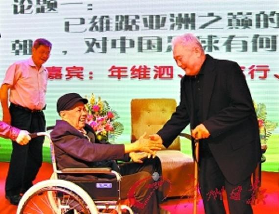 83岁的年维泗（右）拄着拐杖上前与87岁的曾雪麟握手