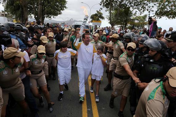 里约市长帕埃斯手持奥运火炬，之前火炬横跨瓜纳巴拉湾由尼泰罗伊传递至里约热内卢。