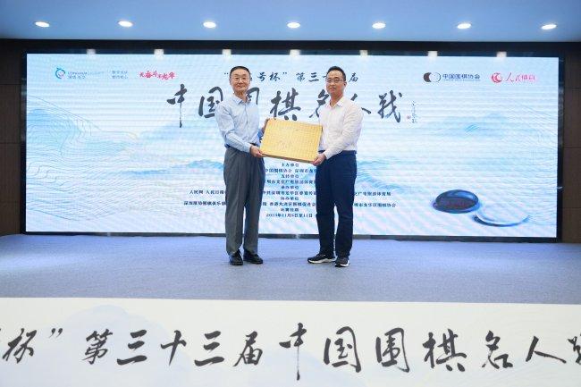 人民日报高级记者、人民体育首席顾问陈昭代表向深圳市龙华区文化广电旅游体育局副局长陈海明赠送签名棋盘