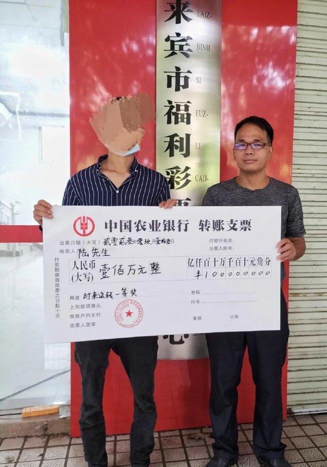 来宾市福彩中心工作人员向陆先生(左一)颁发奖金转账支票