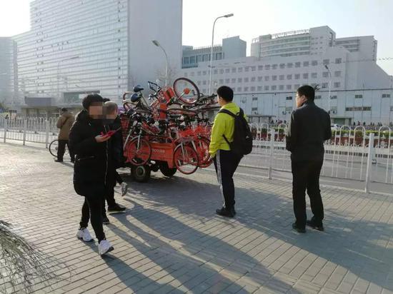 (多位行人在等候即将投放的单车)