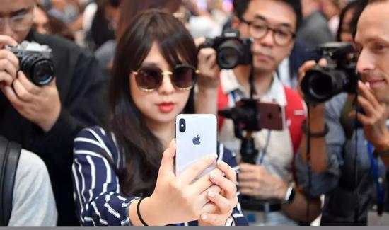 一位正在试用iPhone X的女记者。@视觉中国