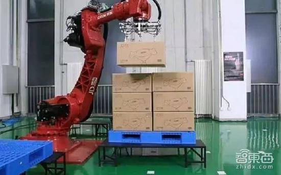 京东无人仓内六轴机器手臂在码放货物,右侧货架由Shuttle货架穿梭车负责搬运