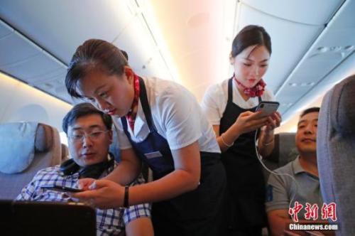 资料图:乘务员们在客舱内为旅客调试机上上网功能。中新社记者 殷立勤 摄