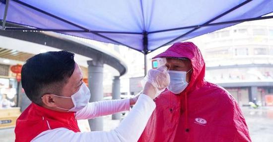 志愿者在为居民测体温(图片来源:新华网 肖和勇摄)