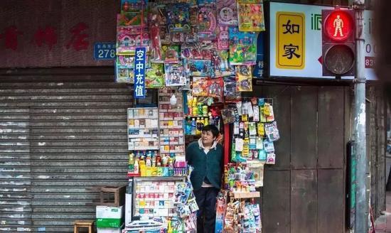 ▲广州市荔湾区长寿东路,一家只能容纳一人的小小士多店。摄于2017年3月25日。图片来源:中国摄影家协会网。