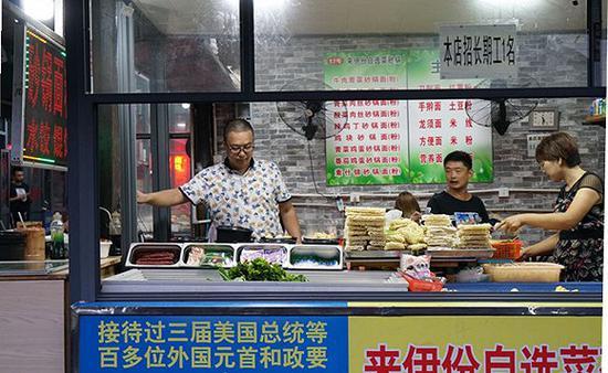 成为的摊前,挂着夸张、滑稽的广告。杨舒鸿吉摄