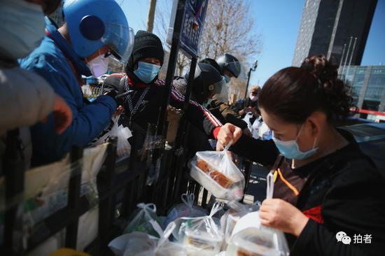 △ 3月13日中午,上地十街,外卖员们在一栋汇聚众多餐饮店的商业大楼围栏外领取店家送出来的订单,该商业大楼暂不对外开放。