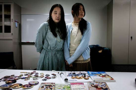 Utano和Prince Sama是乙女向游戏的忠实玩家。在一场乙女向文化研究报告会上,她们俩站在很多游戏周边前面。图片来源:LOULOU D’AKI