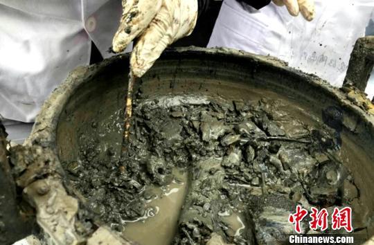 图为考古专家对挖掘出的大鼎内的“肉汤”。 河南省文物考古研究院供图