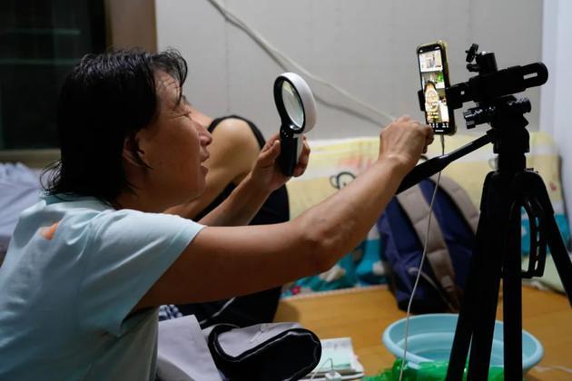 直播中,英姐拿放大镜看手机屏幕上的文字。本文照片均由中青报·中青网记者杨海/摄