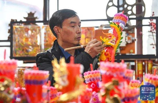 ↑1月25日,陈建友在工作坊制作龙凤花烛产品。