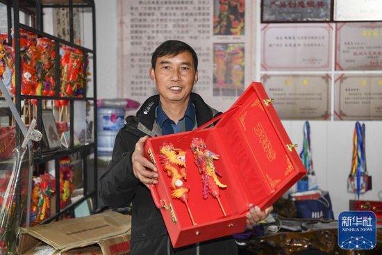 ↑1月24日,陈建友在工作坊展示龙凤花烛产品。
