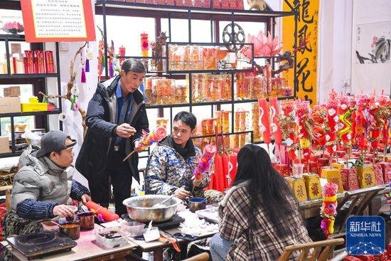 ↑1月25日,陈建友(左二)和工作坊成员交流龙凤花烛制作技巧。
